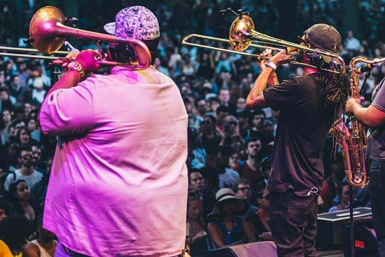 Four men playing brass instruments for a large crowd